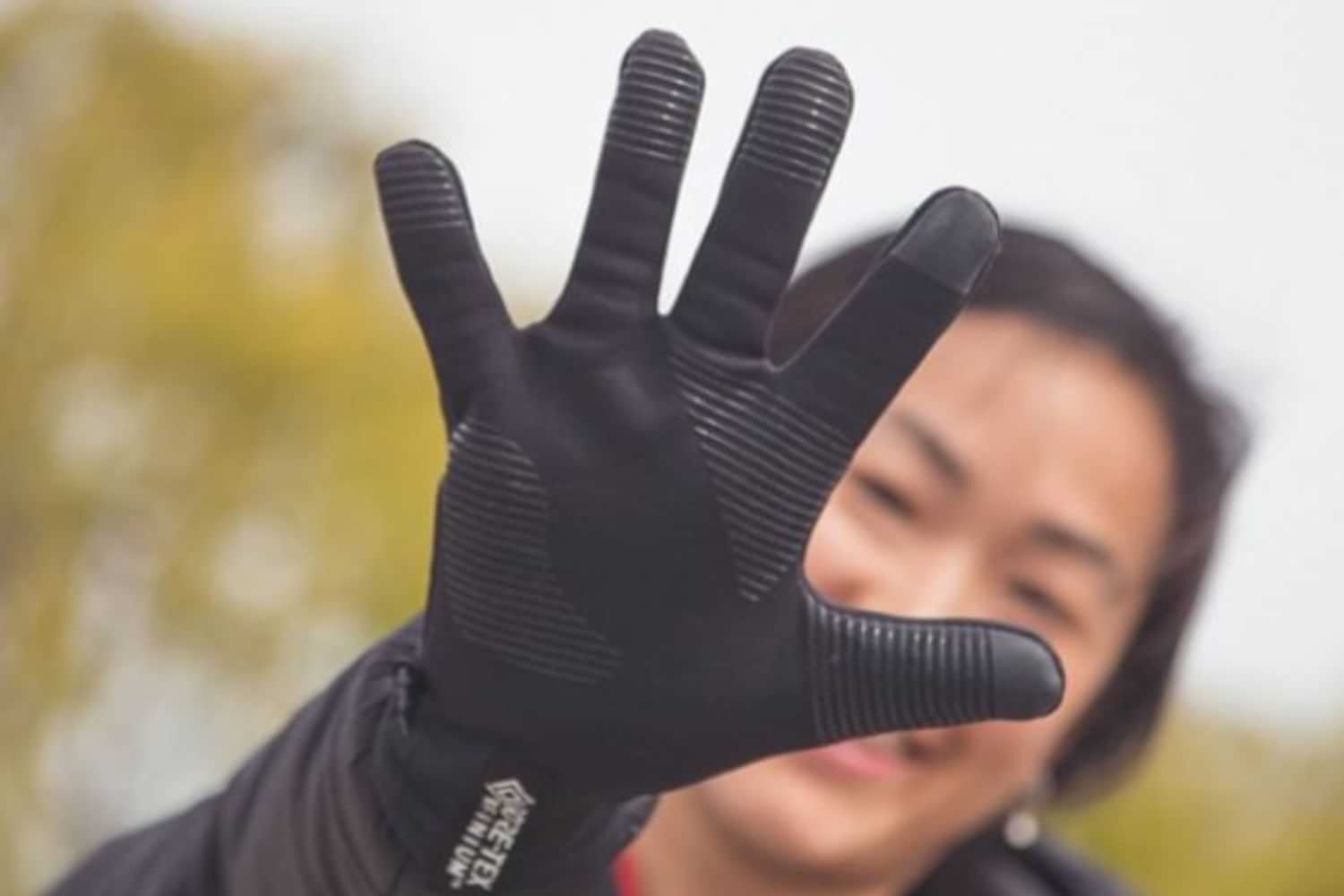 Woman wearing black thermal touchscreen gloves outdoors.