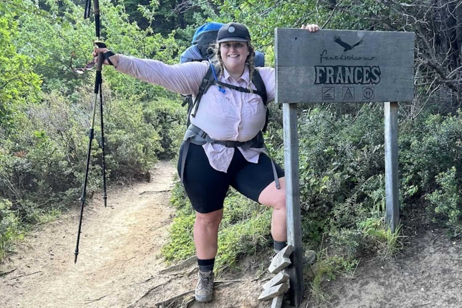 Plus size woman hiking trail with backpack and trekking pole outdoors.