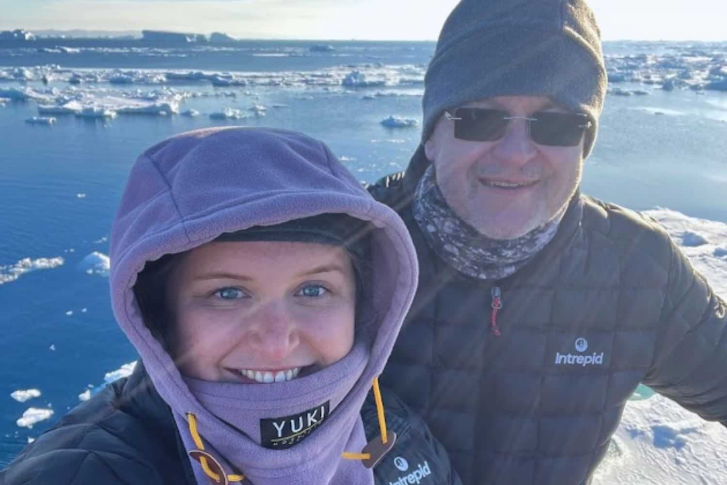 Plus-size daugter and dad in winter clothing exploring icy Antarctica landscape.