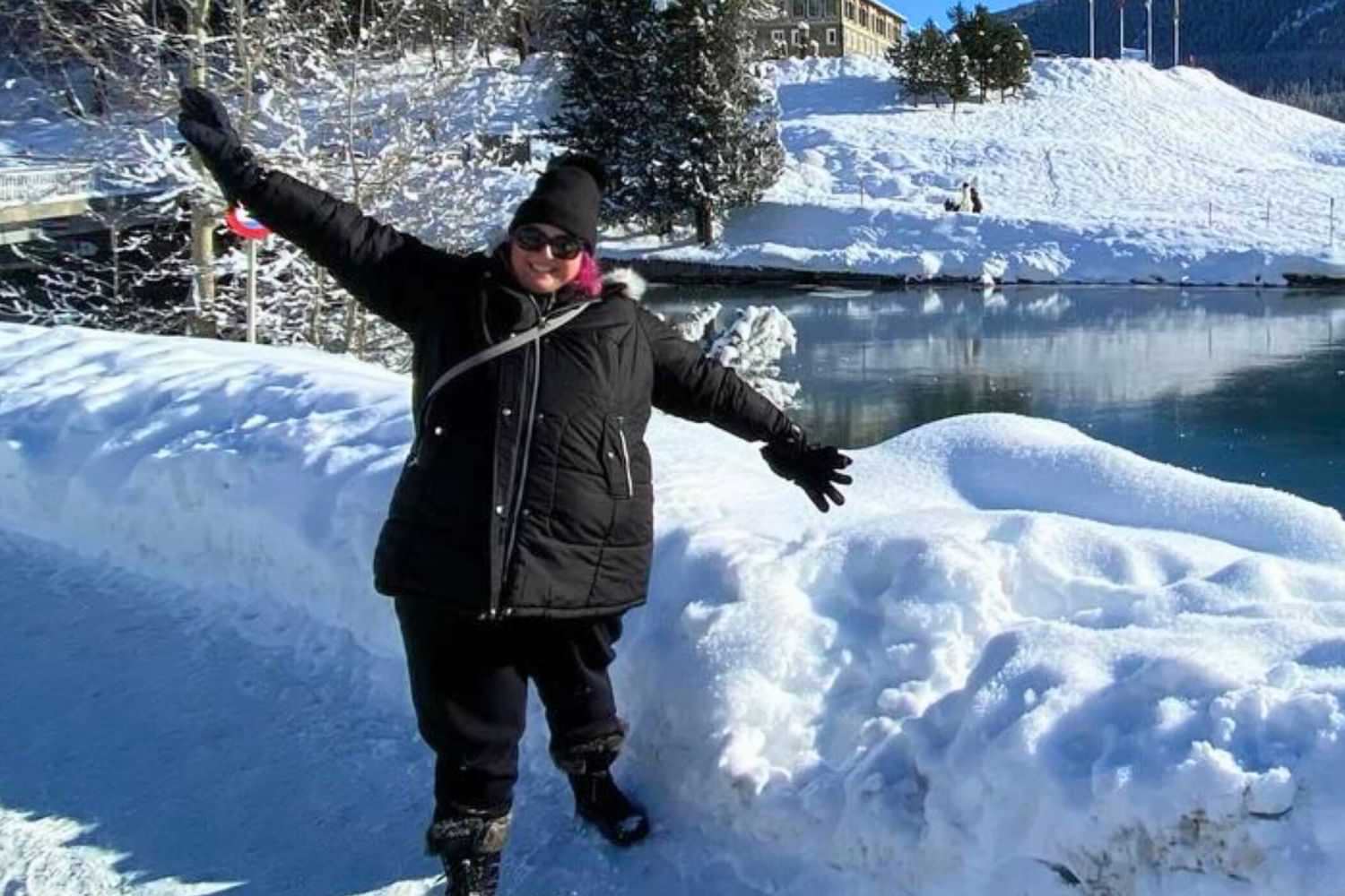 Plus size woman in winter snow gear by snowy lakeside.