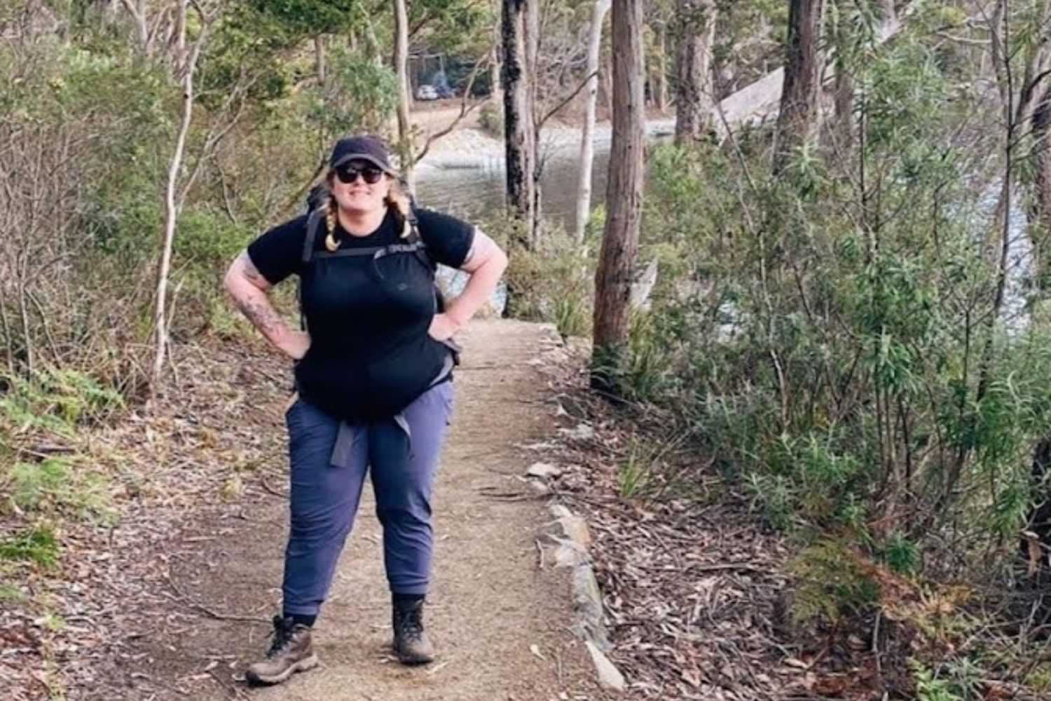 Plus size woman hiking forest trail in outdoor travel pants.