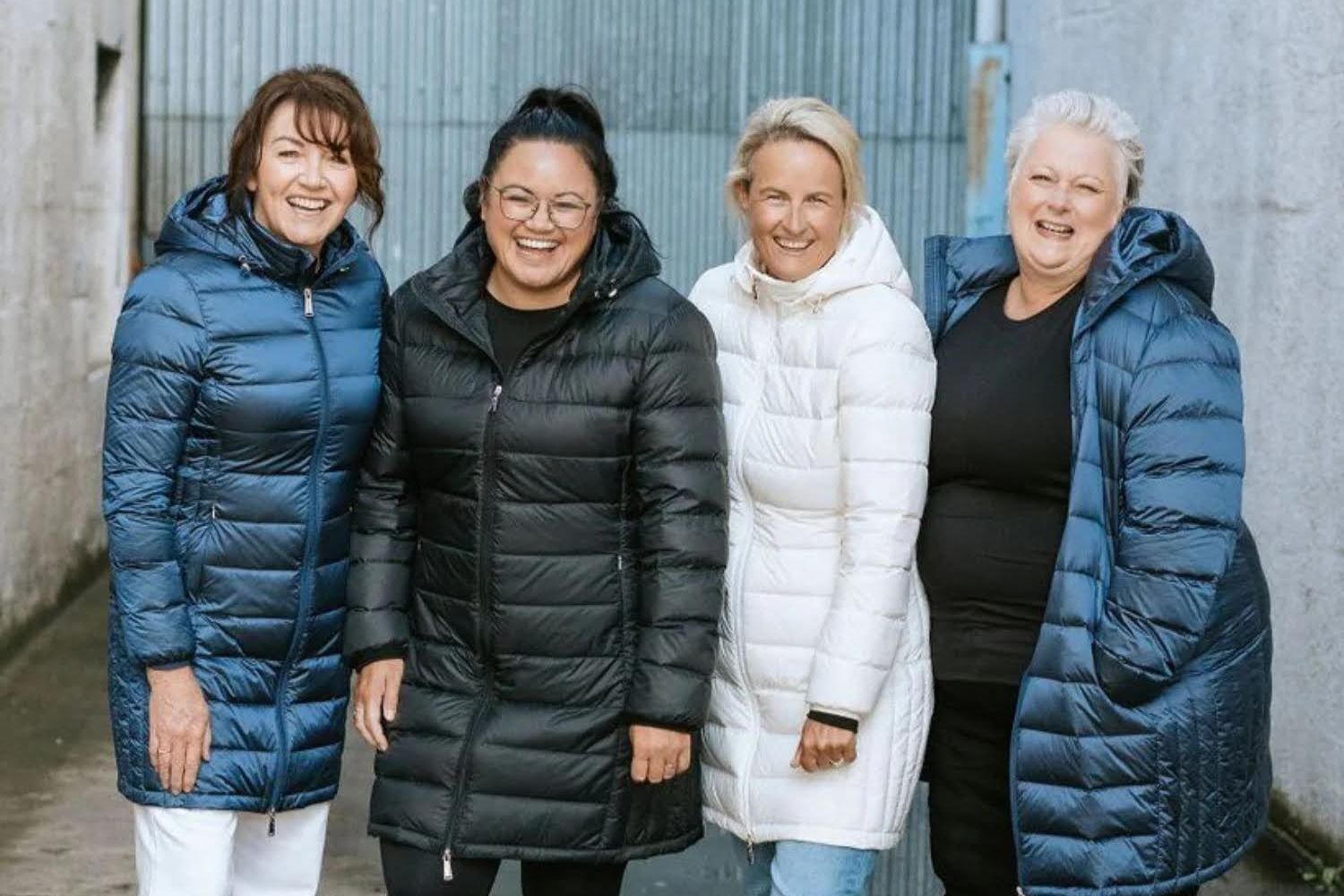 Four women wearing different colours and styles of plus size puffer jackets