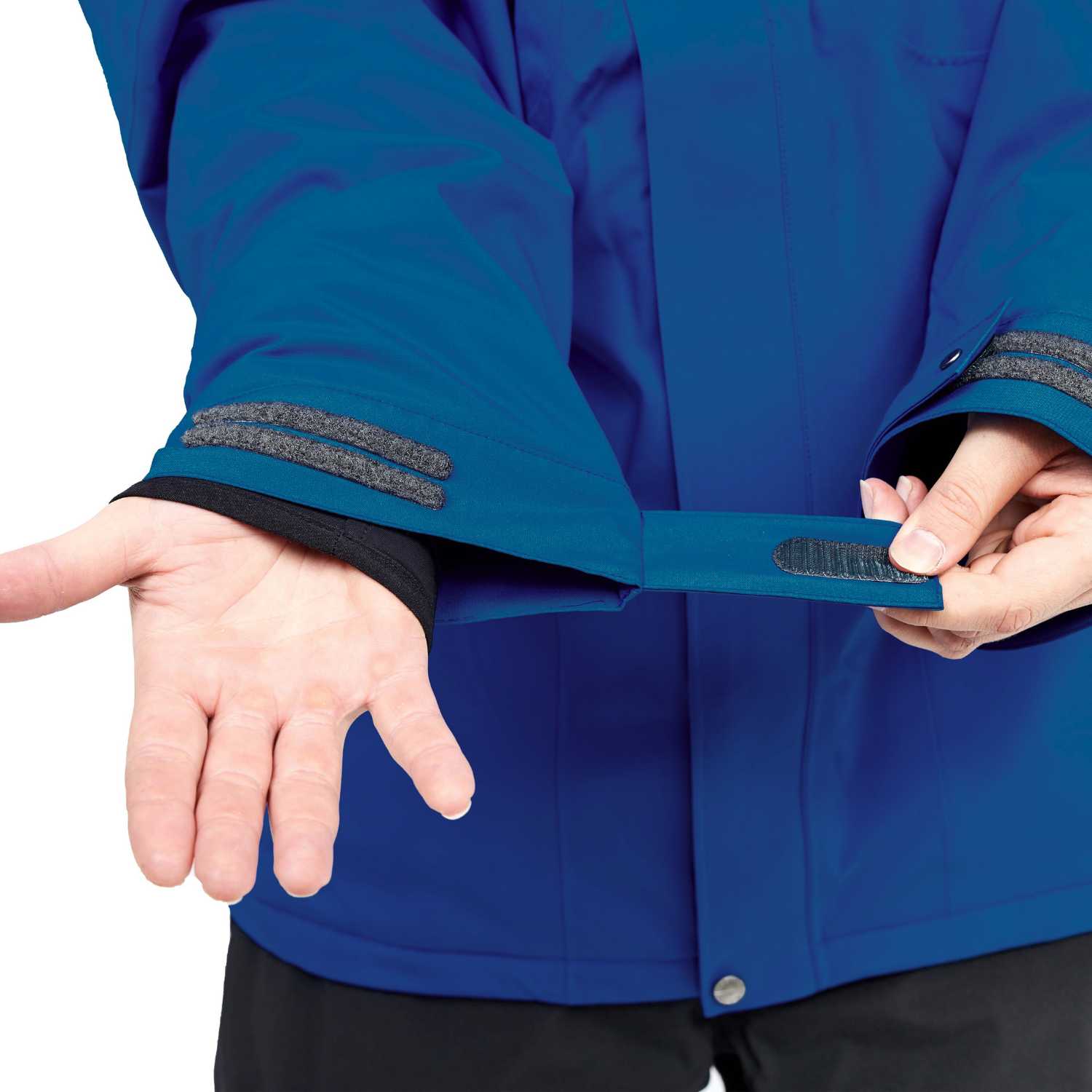 Close-up of a person wearing a blue jacket and demonstrating the adjustable cuff with a hook-and-loop strap, showing the strap being opened and closed.