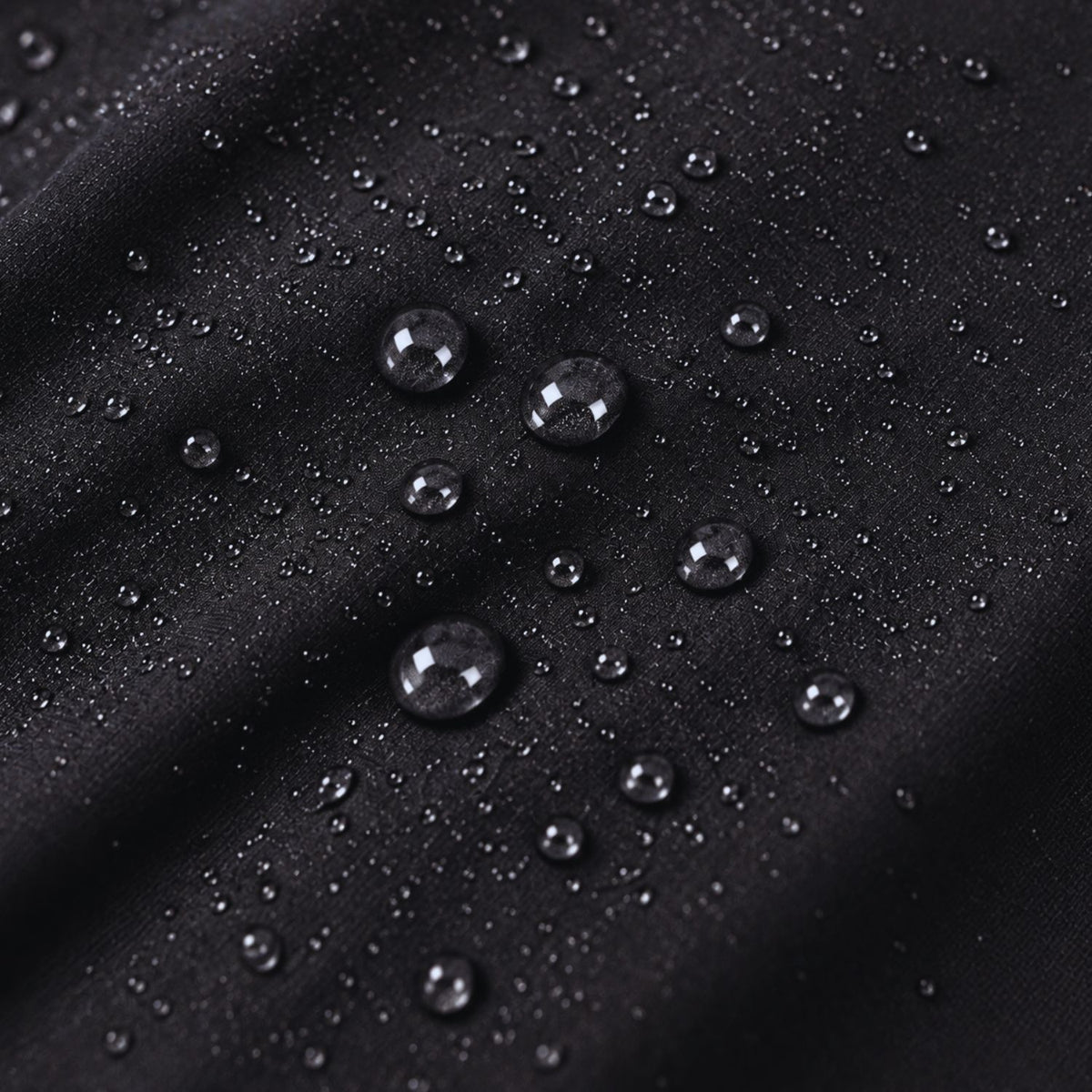 Close-up of a black fabric surface with scattered water droplets, showing a water-repellent or hydrophobic texture.