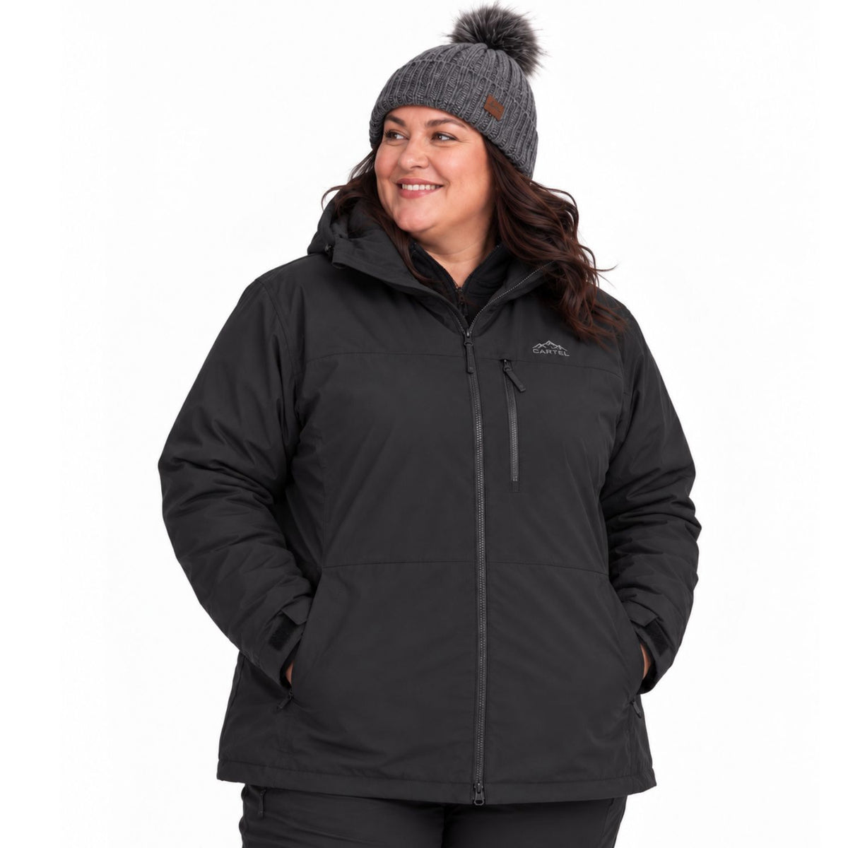 A woman wearing a black hooded zip-up jacket and a gray knit beanie with a pom-pom, photographed against a plain white studio background.