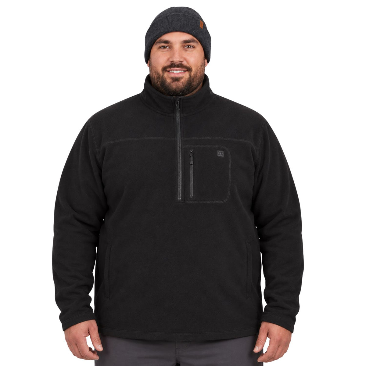 A big man wearing a black quarter-zip fleece pullover and a black knit beanie, standing against a plain white background.
