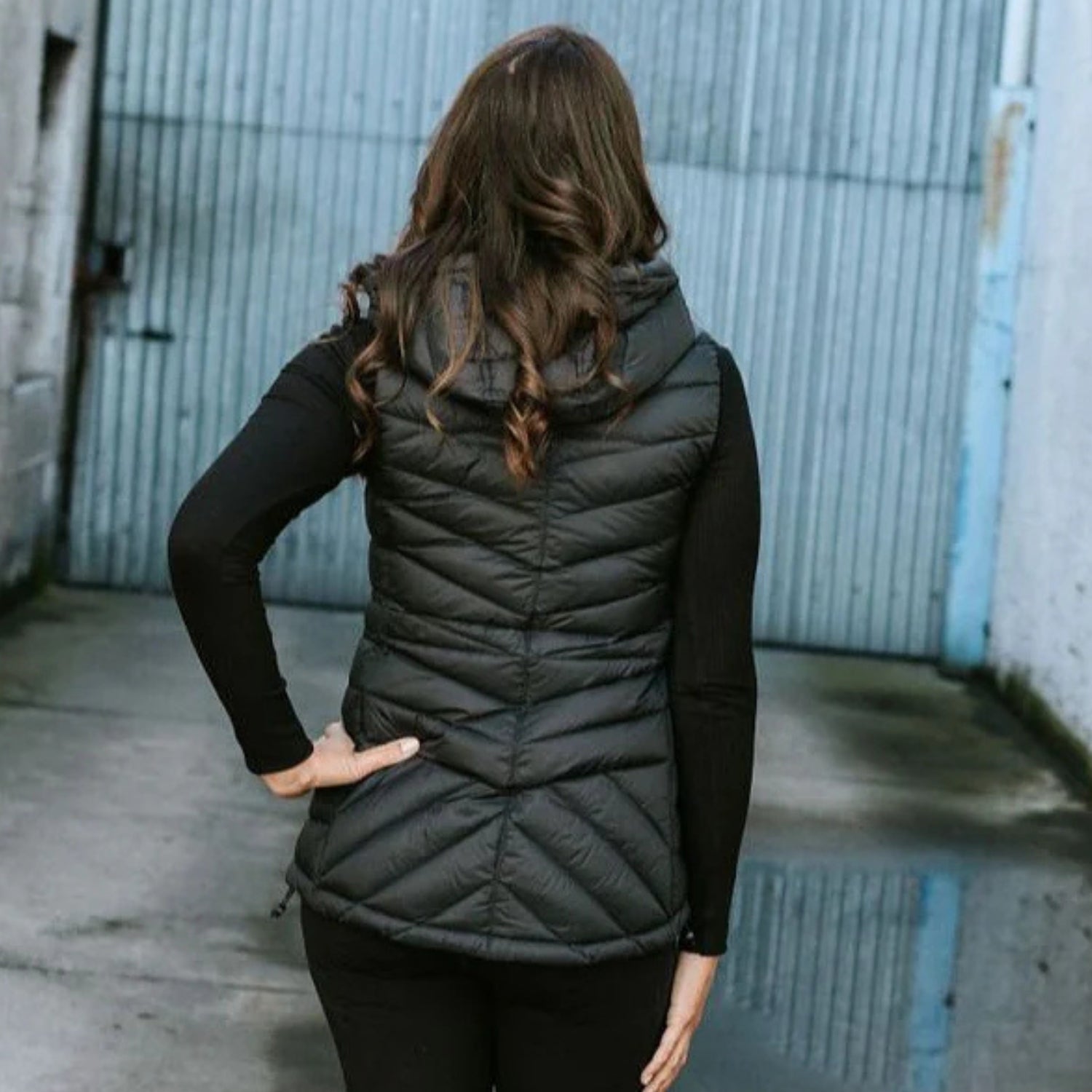 woman facing back wearing a Moke black down puffer vest, showing the back of a plus size clothing as sold on Plus Outdoor