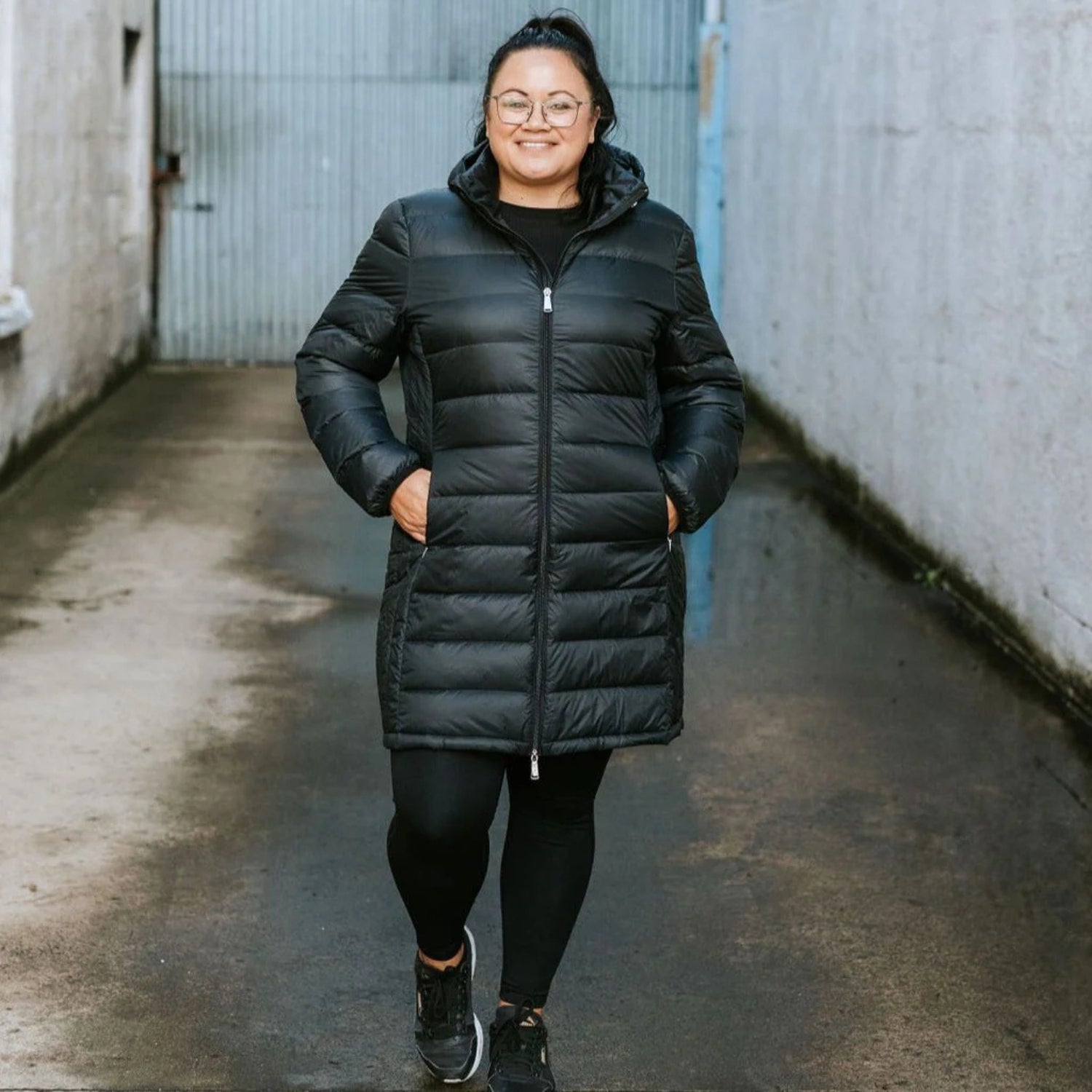 Woman with glasses walking wearing long down Sydney Plus size jacket.