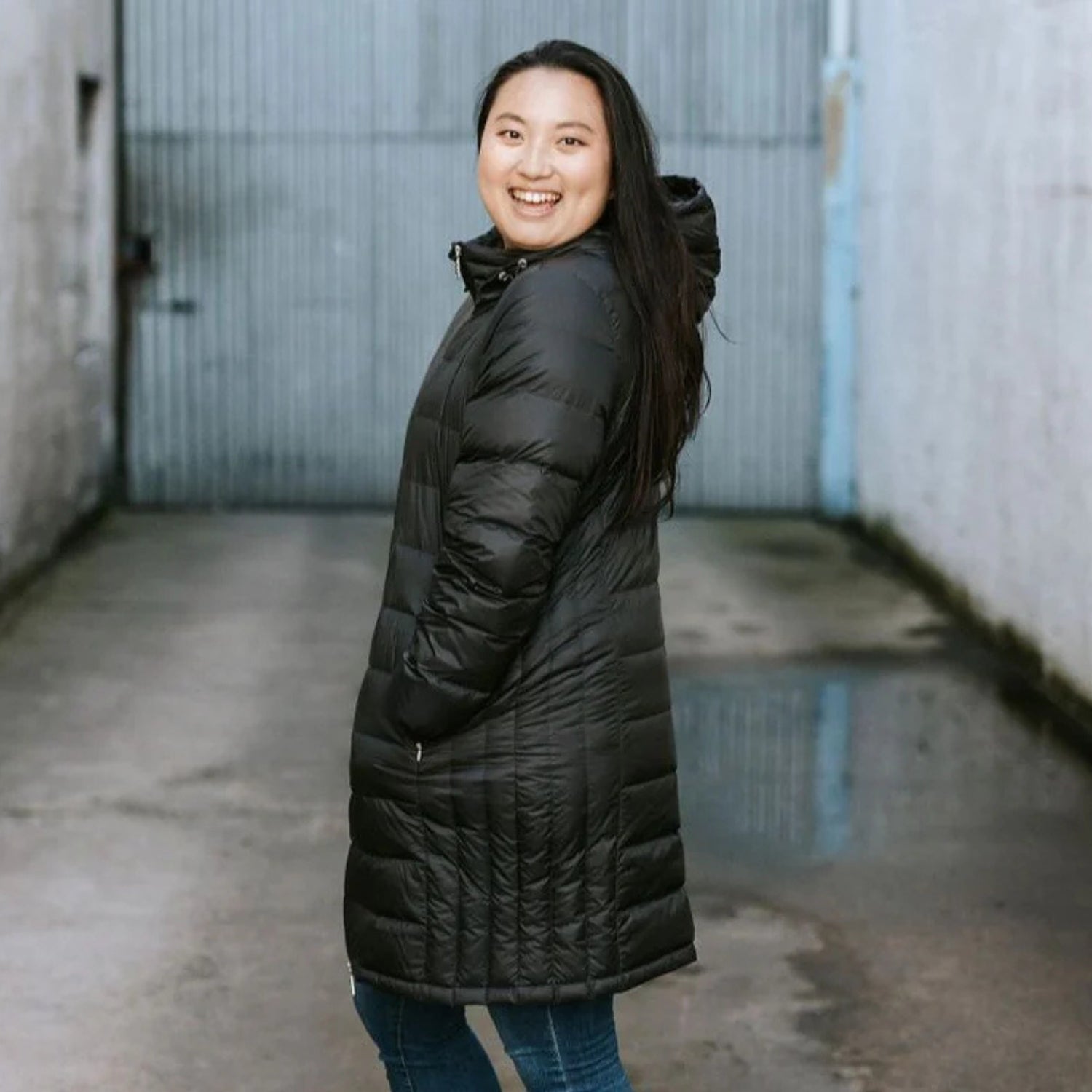Woman wearing long down Sydney Plus size jacket, side view.
