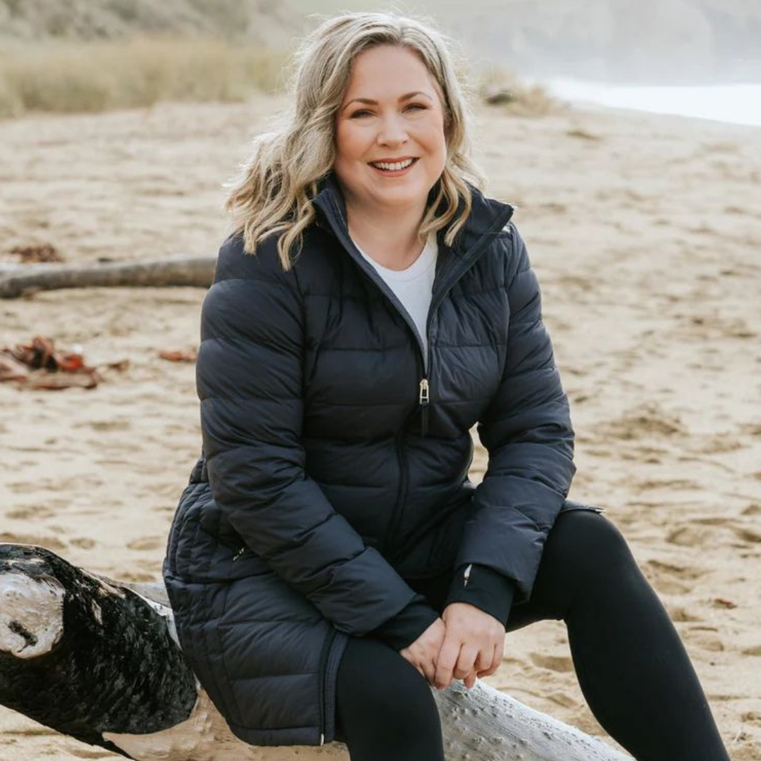 Plus Size Woman sitting on the beach wearing a Moke Down Puffer Sydney black plus size jacket