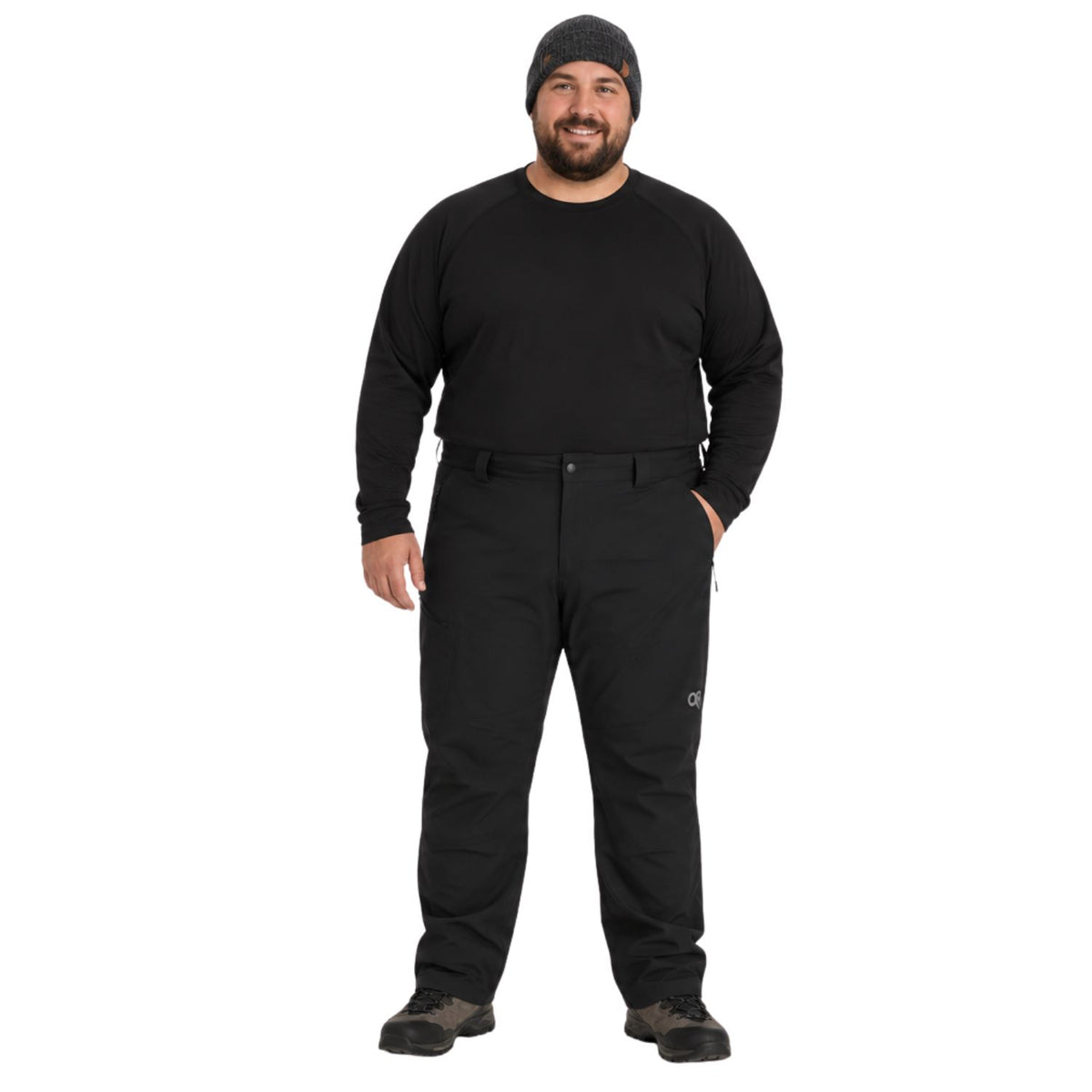 A big man wearing a black long-sleeve crewneck shirt, black pants, and a black beanie, standing against a solid white background.