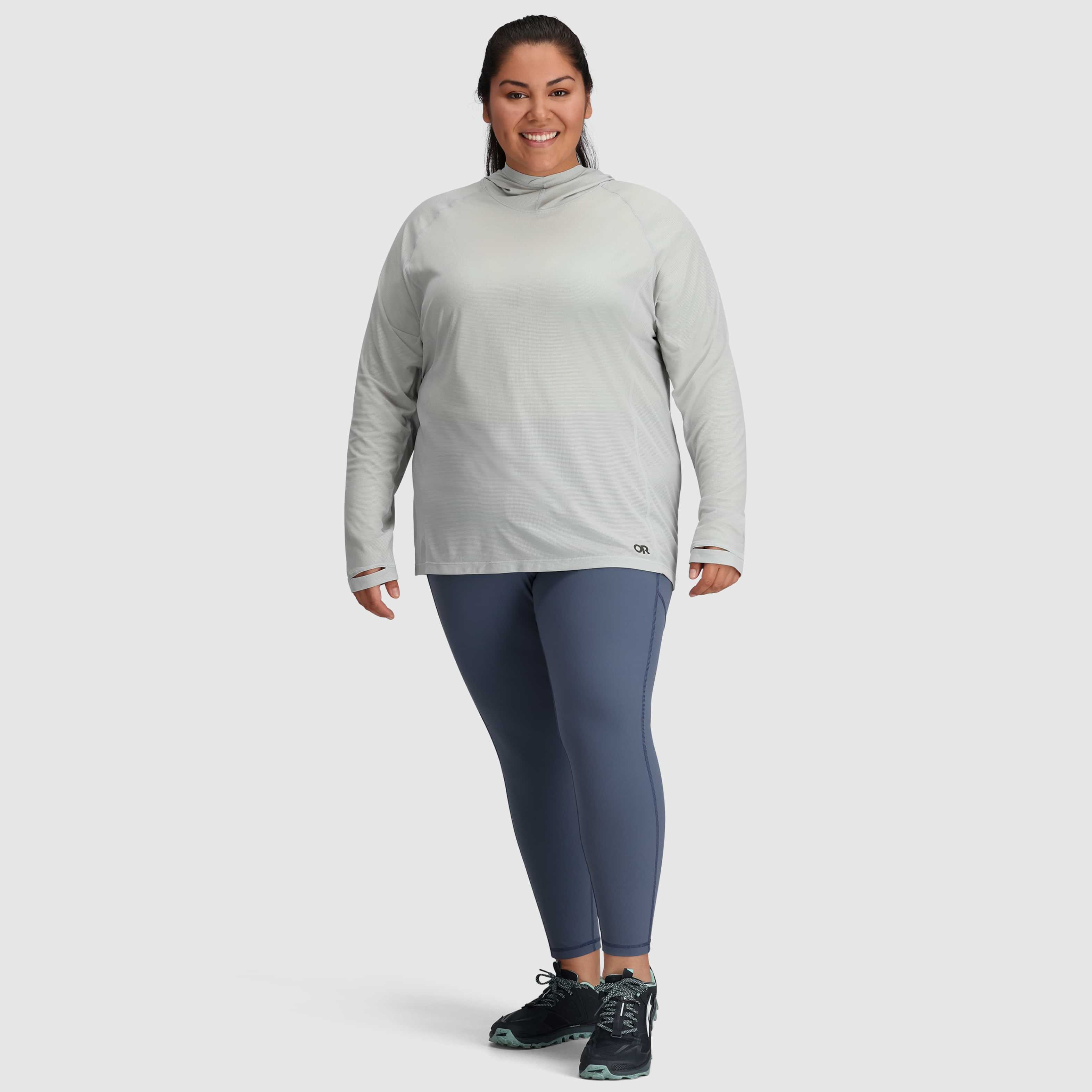 Person wearing a gray long-sleeve top and blue leggings on a white background