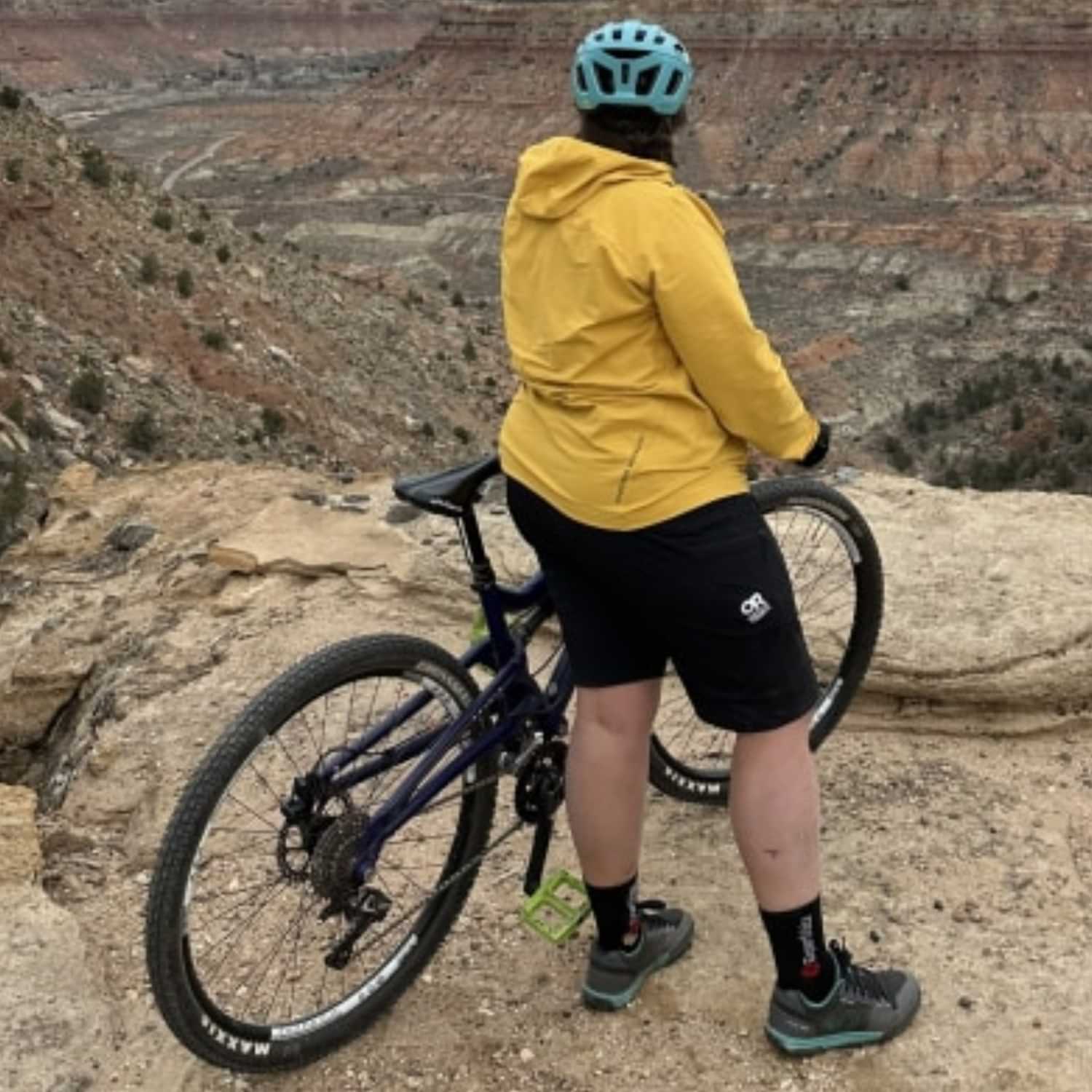 Plus size cyclist overlooking a canyon trail wearing Outdoor Research Freewheel Women’s Plus Size Shorts in black, designed for biking, hiking, and active outdoor adventures.