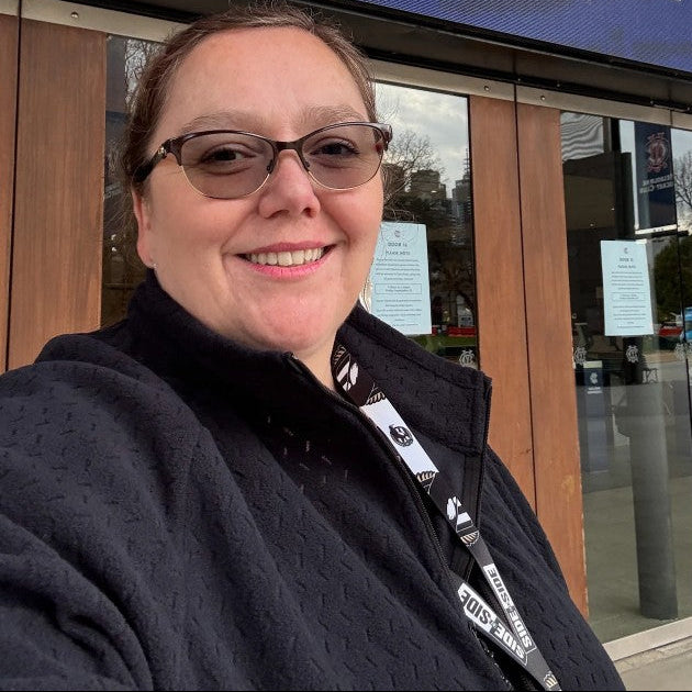 Plus size person wearing glasses and a black fleece jacket in front the MCG in Melbourne