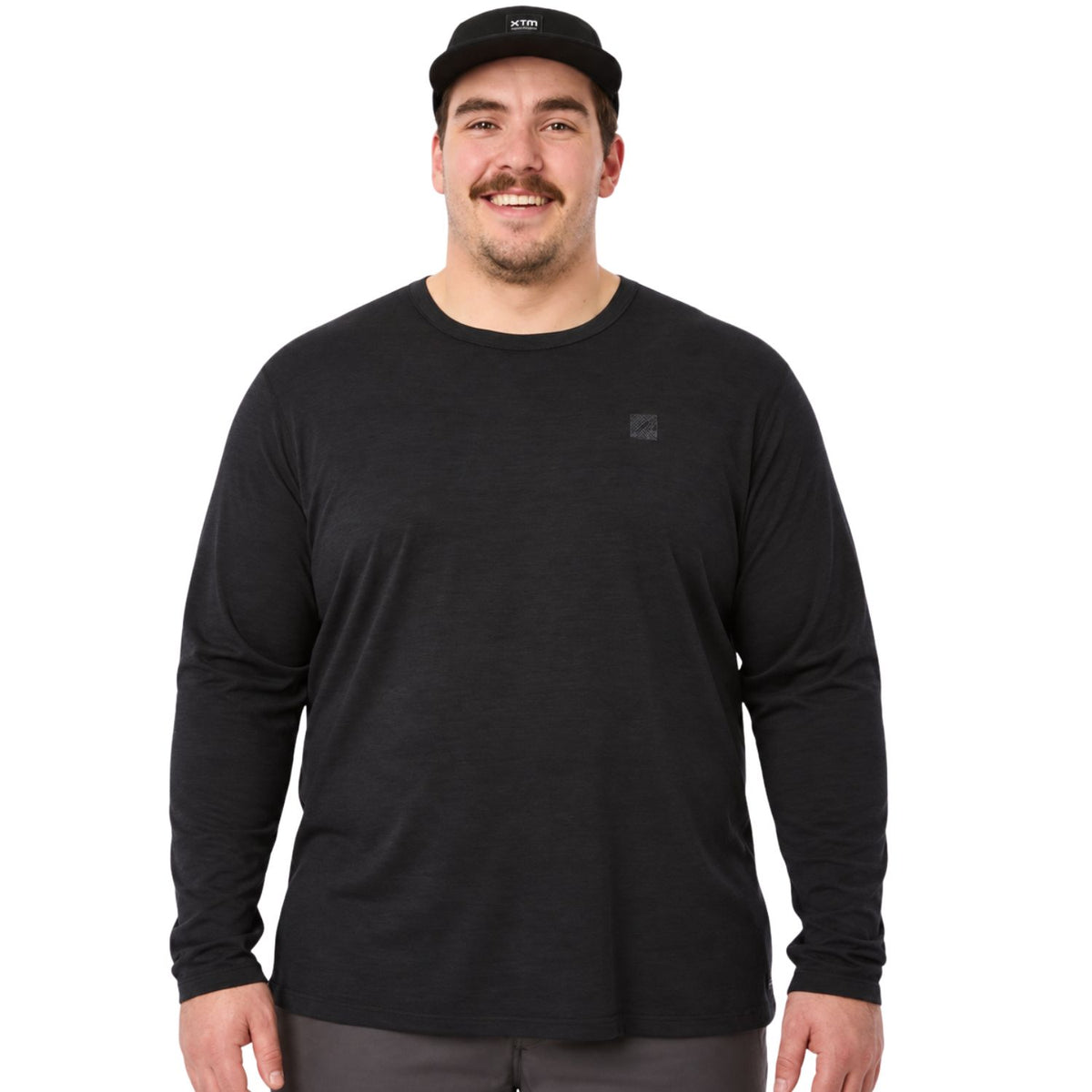 An extra large man wearing a black long-sleeve crewneck shirt and a black baseball cap, standing against a solid white background.