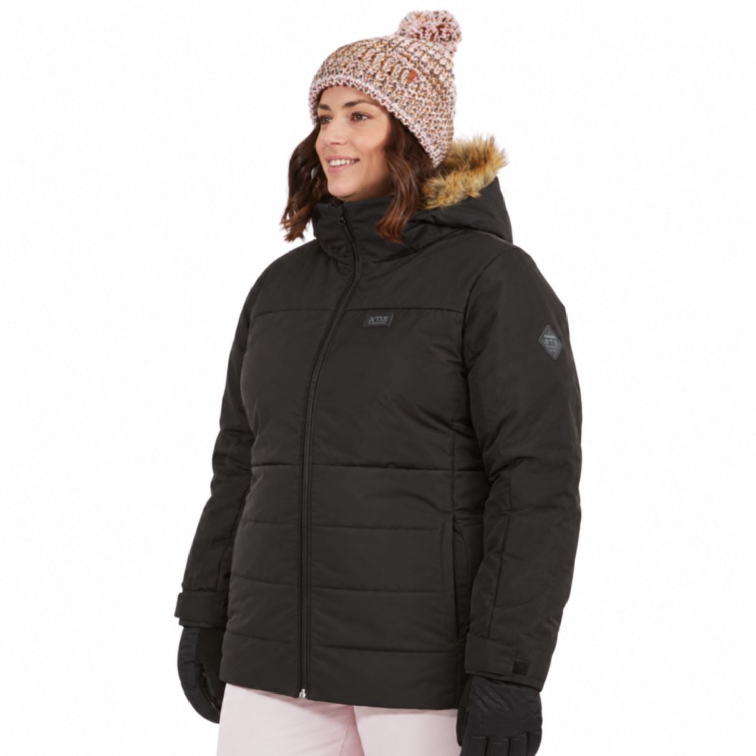 A plus size woman wearing a black XTM quillted snow jacket with a brown faux-fur trimmed hood, a knit beanie, and gloves, shown against a plain white background.