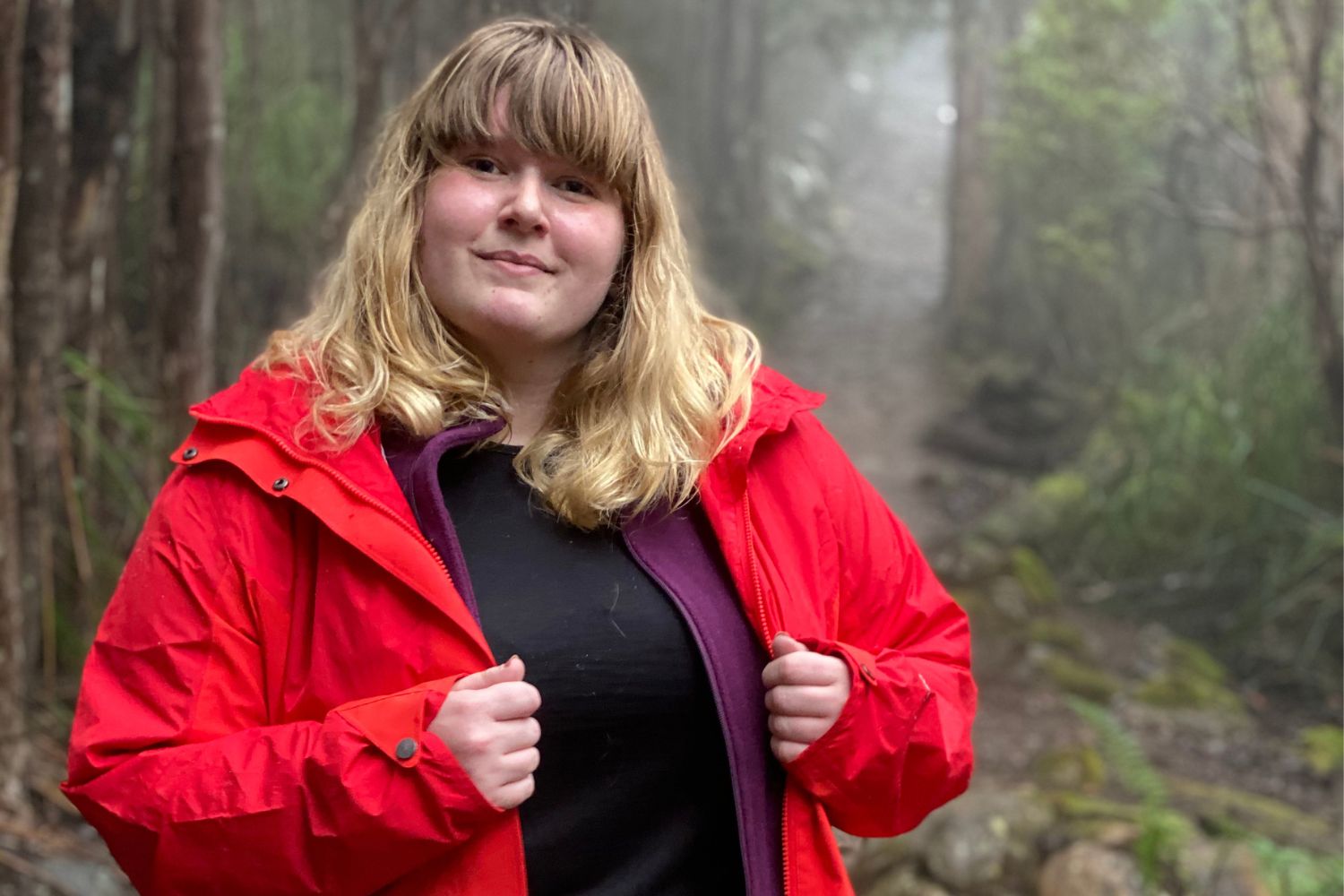 plus size woman in a misty forest scene showing us her layering clothing
