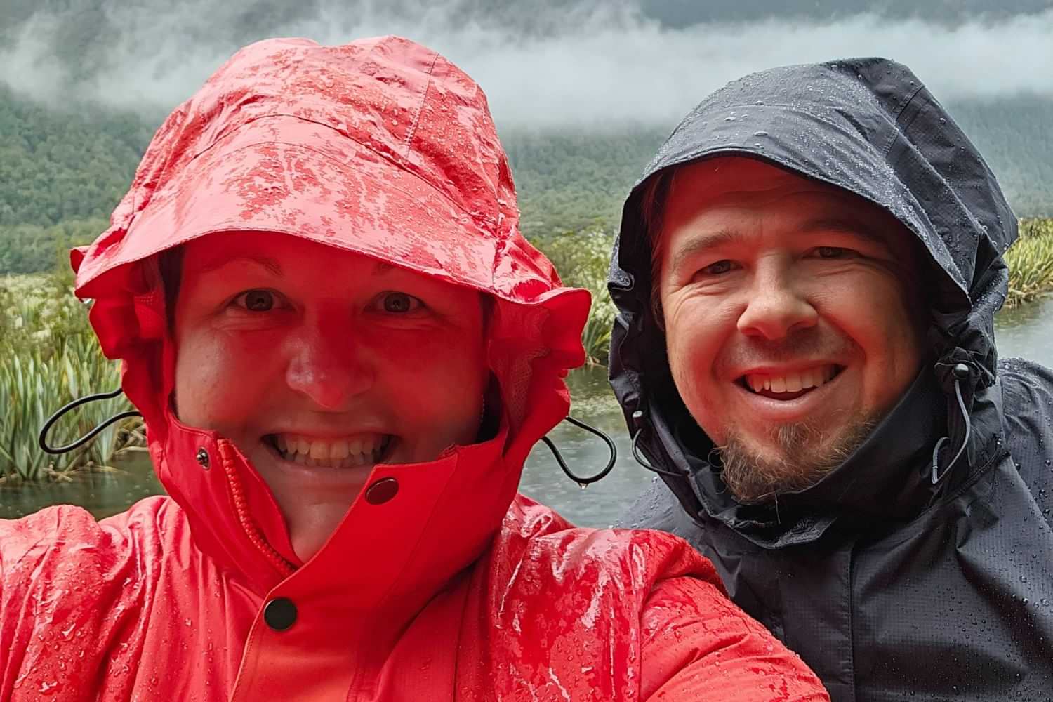 Plus-size woman and man wearing their hoods up in rain jackets