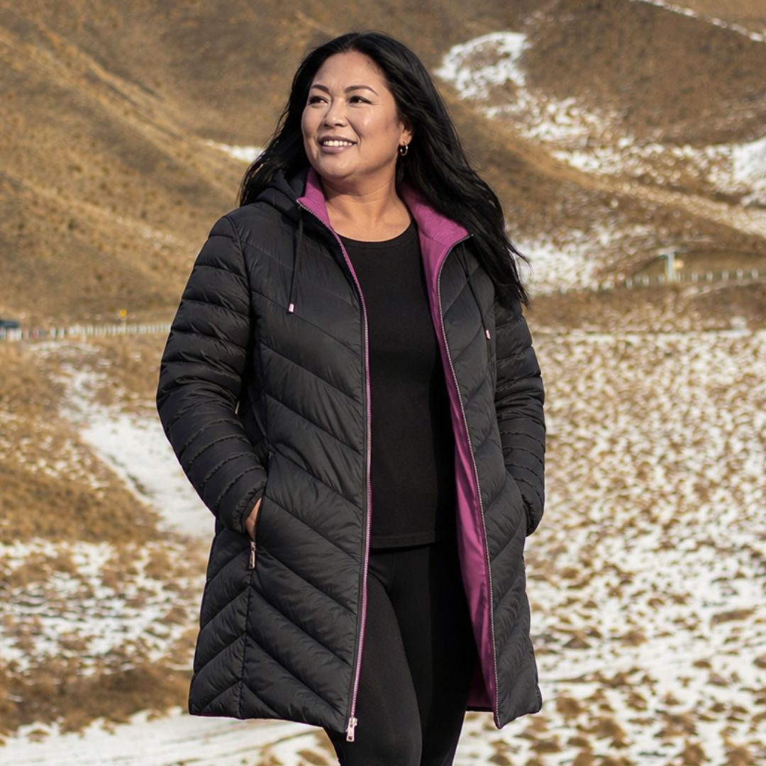 Smiling woman wearing the reversible Moke Arnie Women's Puffer Coat unzipped to show the black exterior and rose violet interior lining.