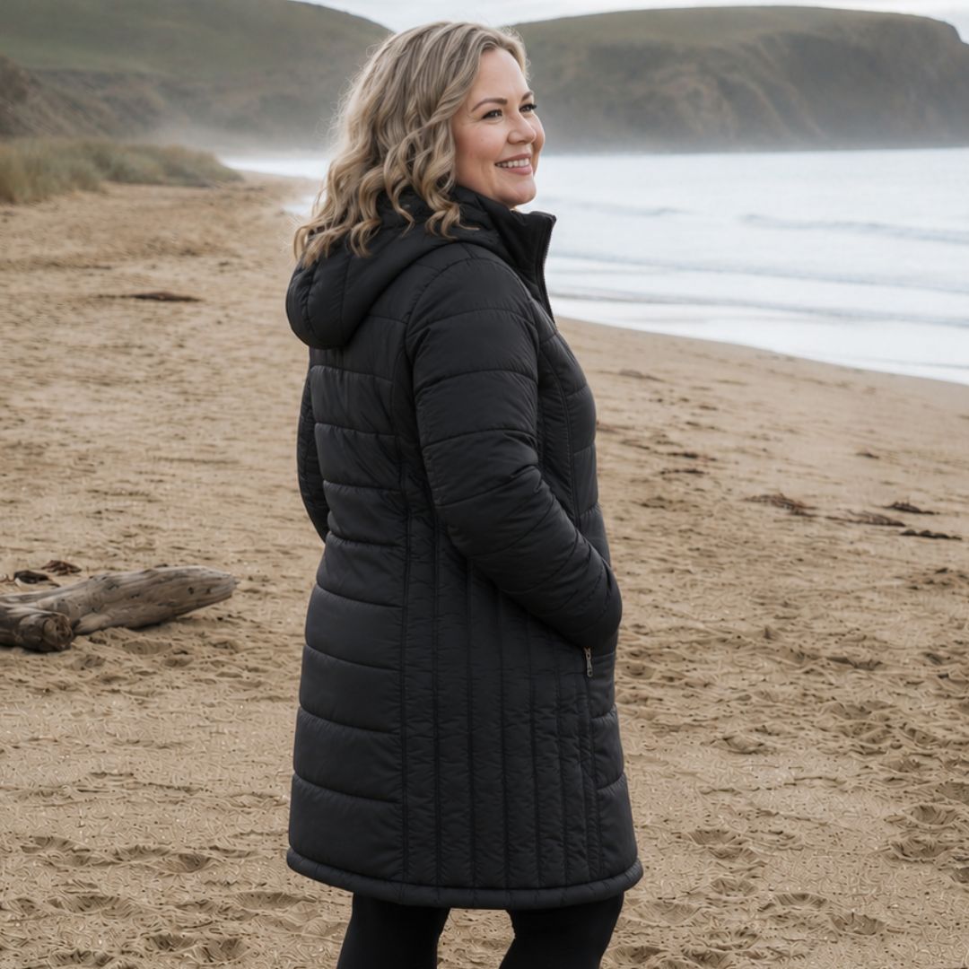 Plus Size Women’s Long Black Puffer Jacket on Beach – Hooded Winter Coat Outdoor Lifestyle Image