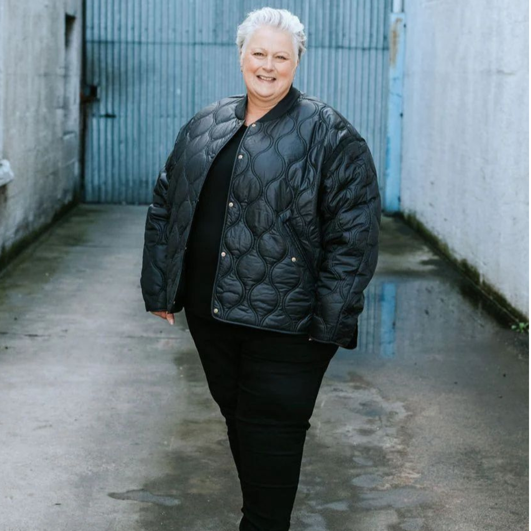 A plus size woman standing wearing the talie quilt black jacket