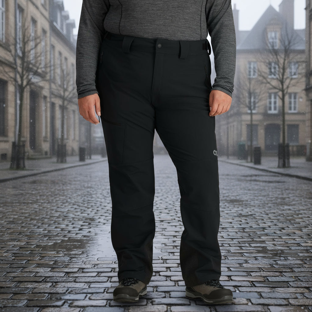 A woman standing, wearing black Outdoor Research Cirque Women's Softshell Pants with a brushed tricot-lined waistband, multiple pockets, and a logo on the left thigh area.