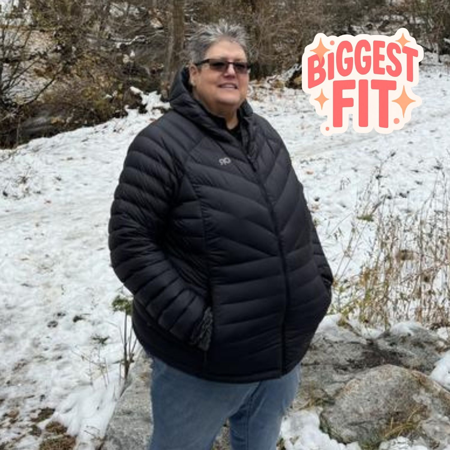 Plus size woman wearing an Outdoor Research black down puffer jacket standing in a snowy landscape