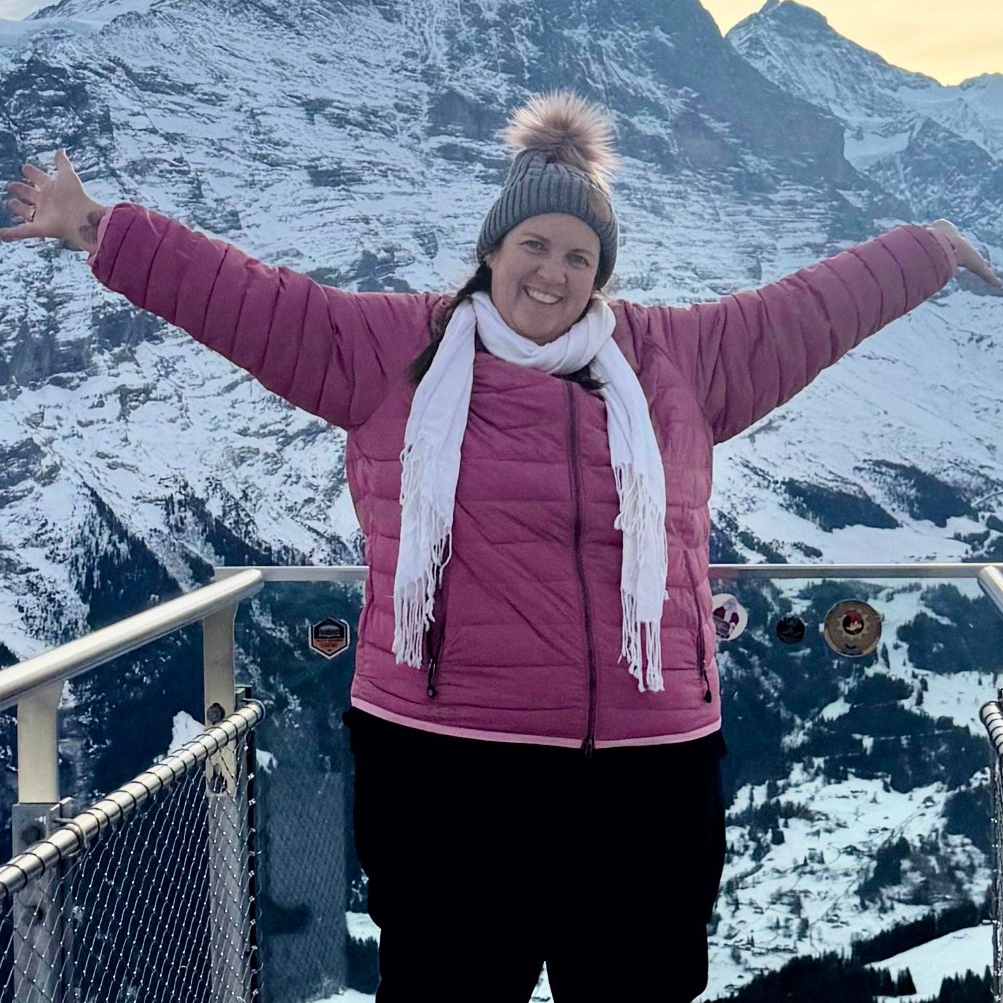 Plus size woman standing  in the mountains with her arms spread wide and big smile 

