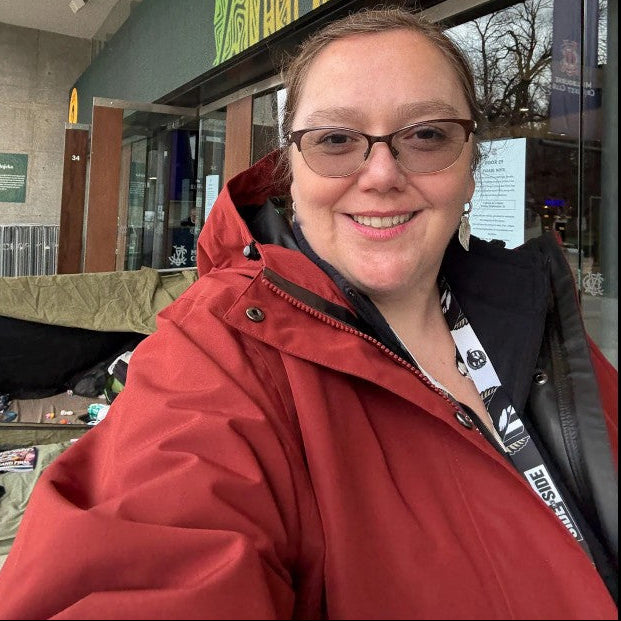 Person wearing a red jacket in front of a building with a decorative facade