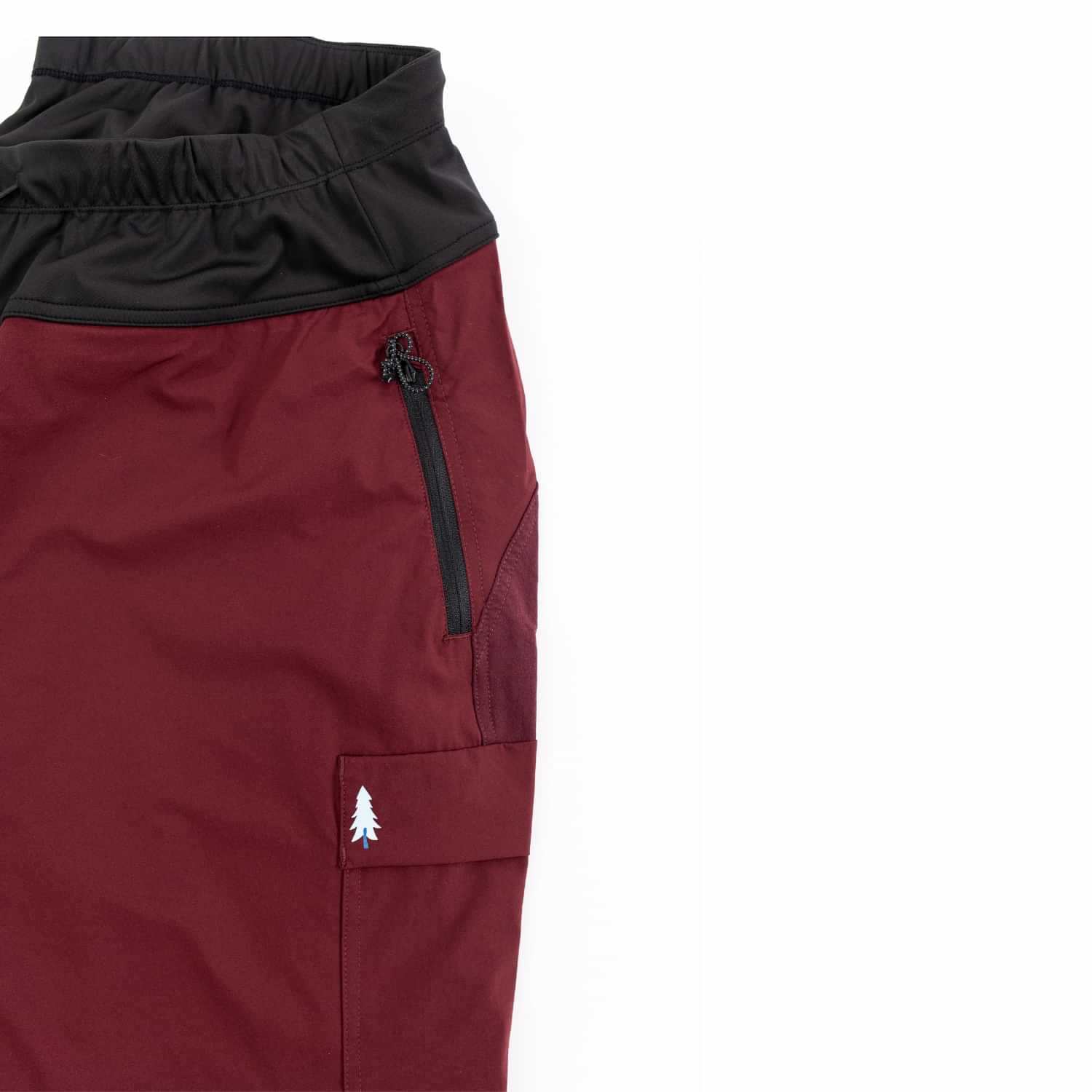Close-up of Thicket Adventure Brecken Hiking Pants BELLY FIT zip pocket and cargo pocket detail in burgundy.