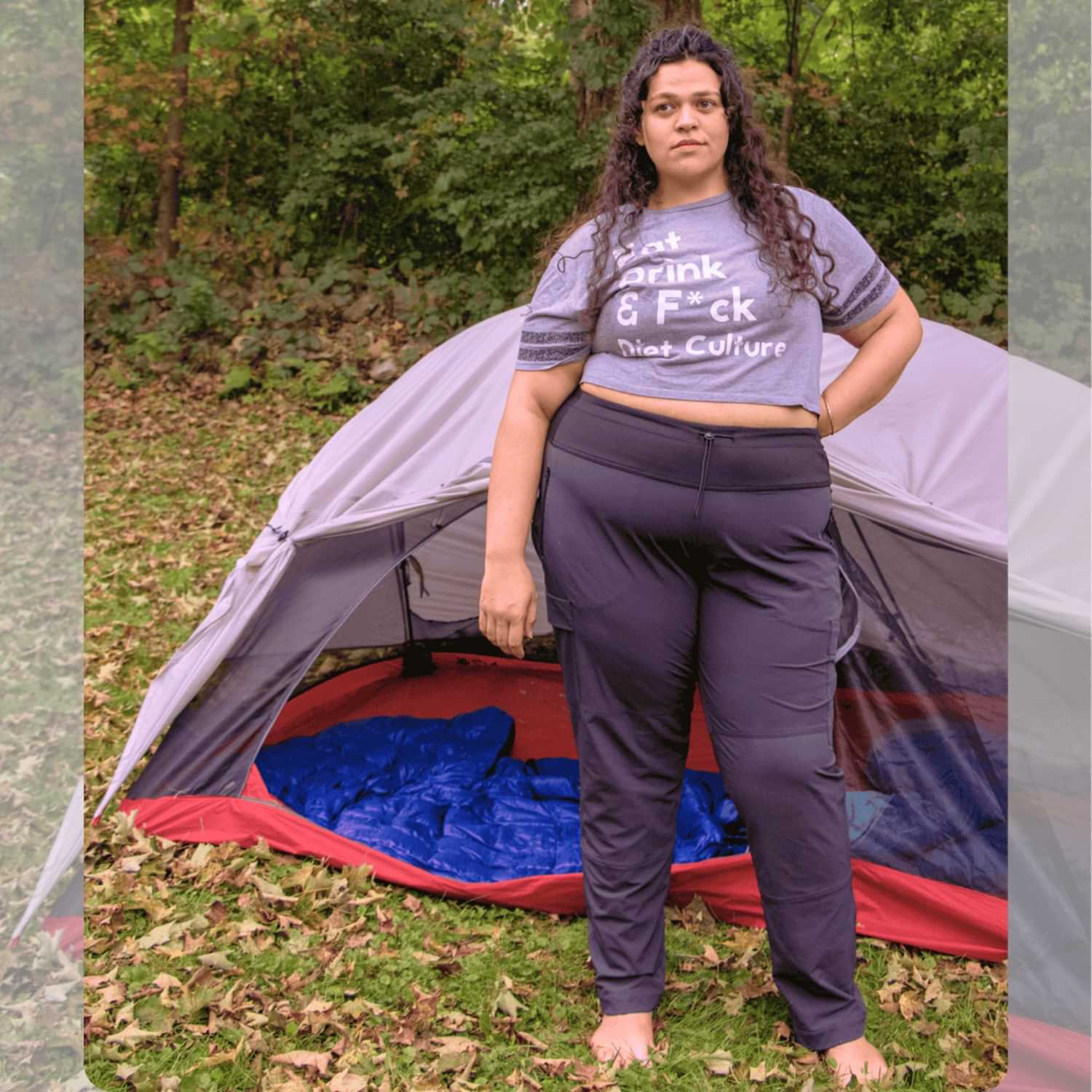 Plus size woman wearing Thicket Adventure Brecken Travel Pants Belly fit in plus sizes 18–34 beside camping tent outdoors.