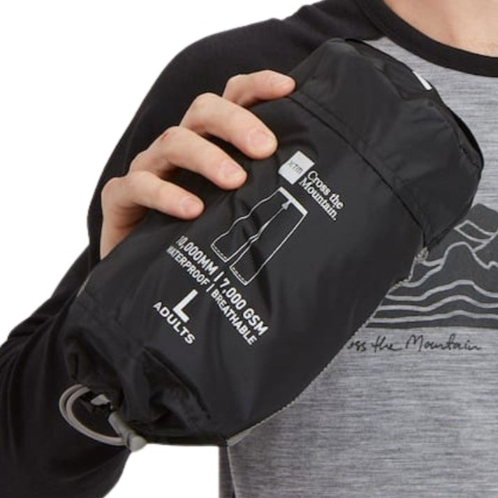 Person holding a pair of packable rain pants with XTM's 'Cross the Mountain' branding on a white background